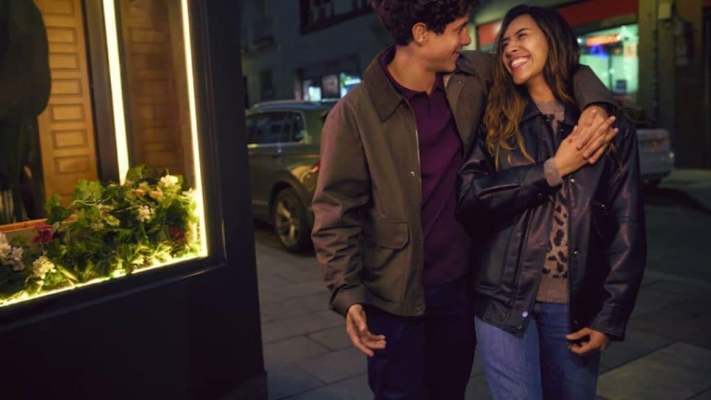 Couple laughing together while walking under city lights