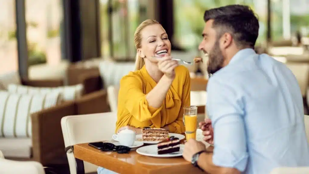 Woman offering a bite of dessert to a man