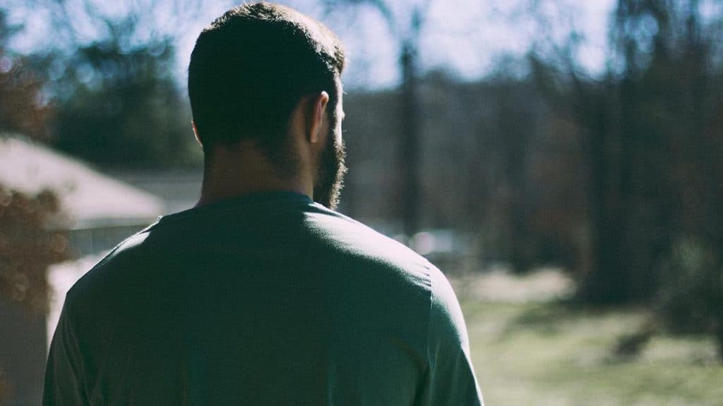 A man standing outdoors with his back to the camera.