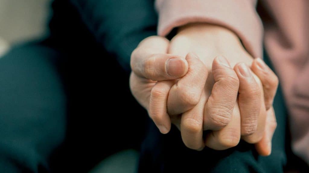 A close-up of two people holding hands tightly.