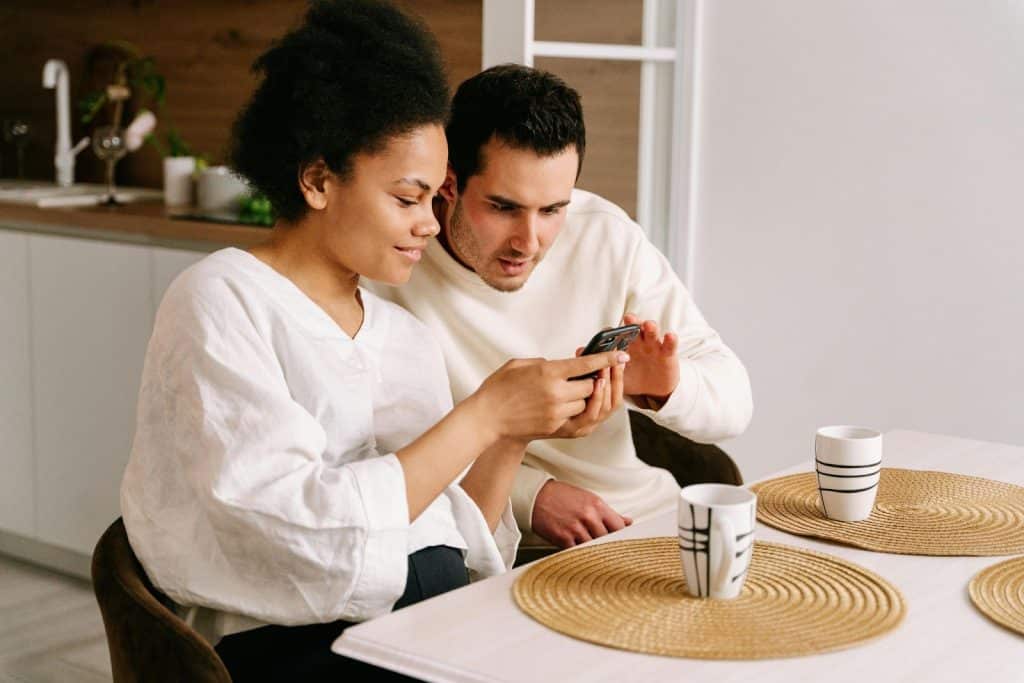 A woman showing something from phone to a man