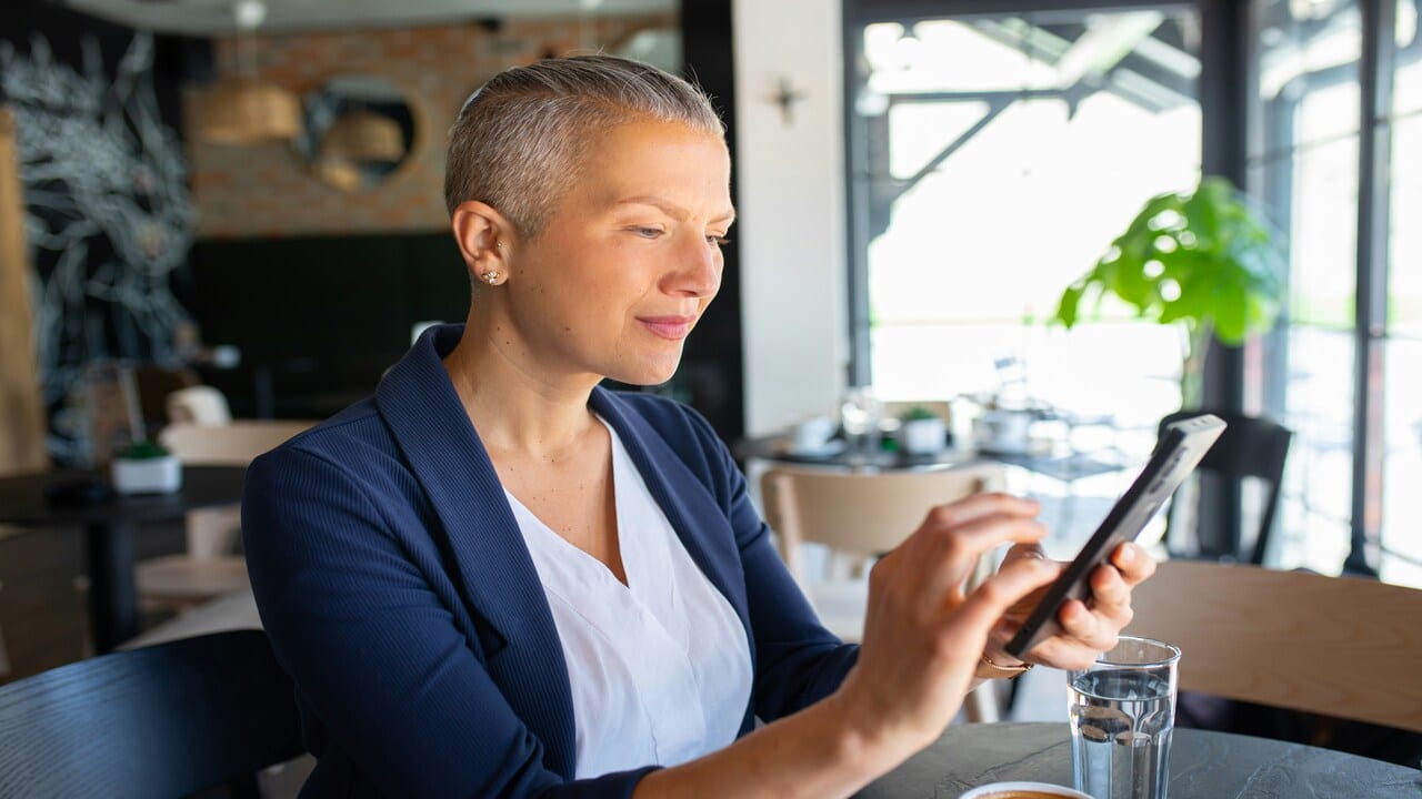 A mature woman looking sadly at her phone.