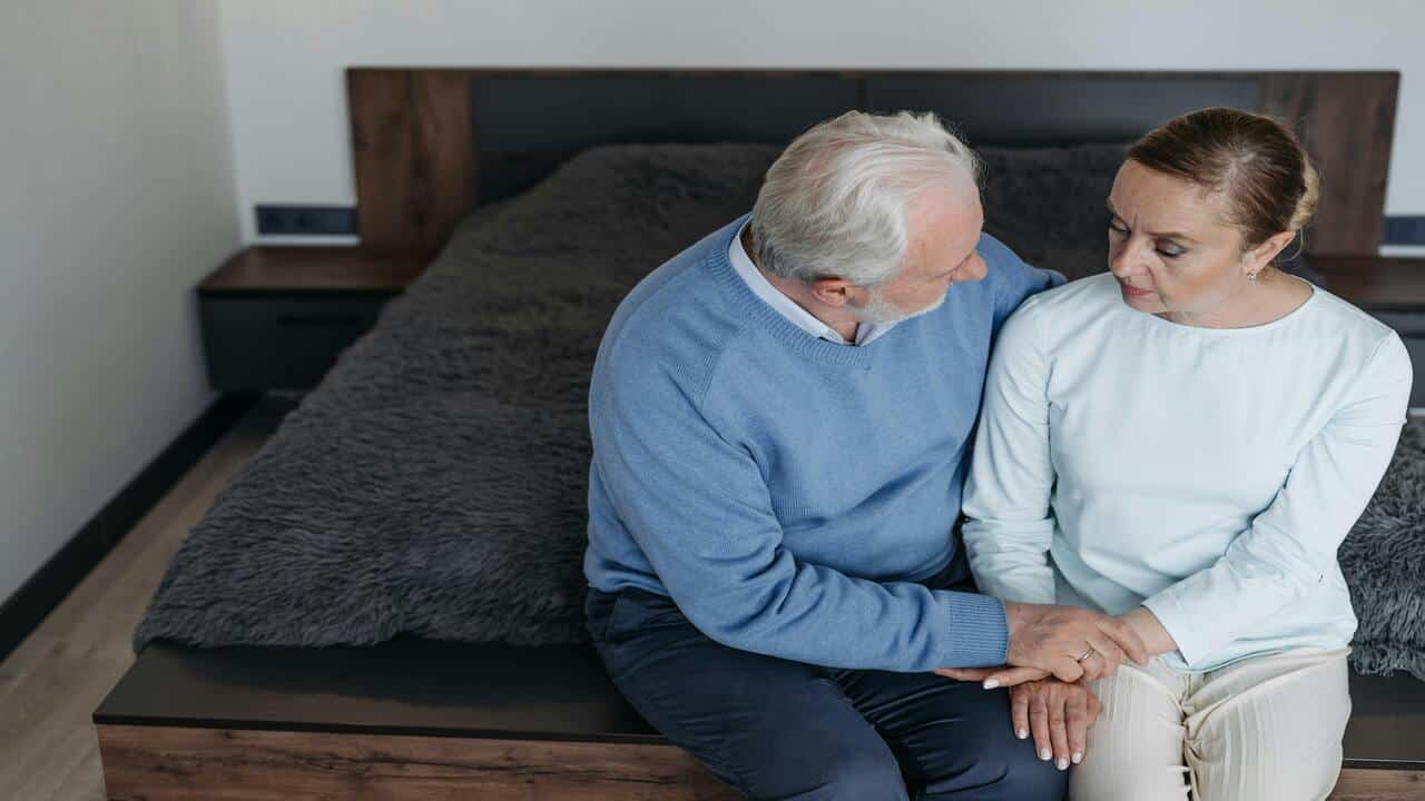 An older couple having a serious talk in the bedroom.