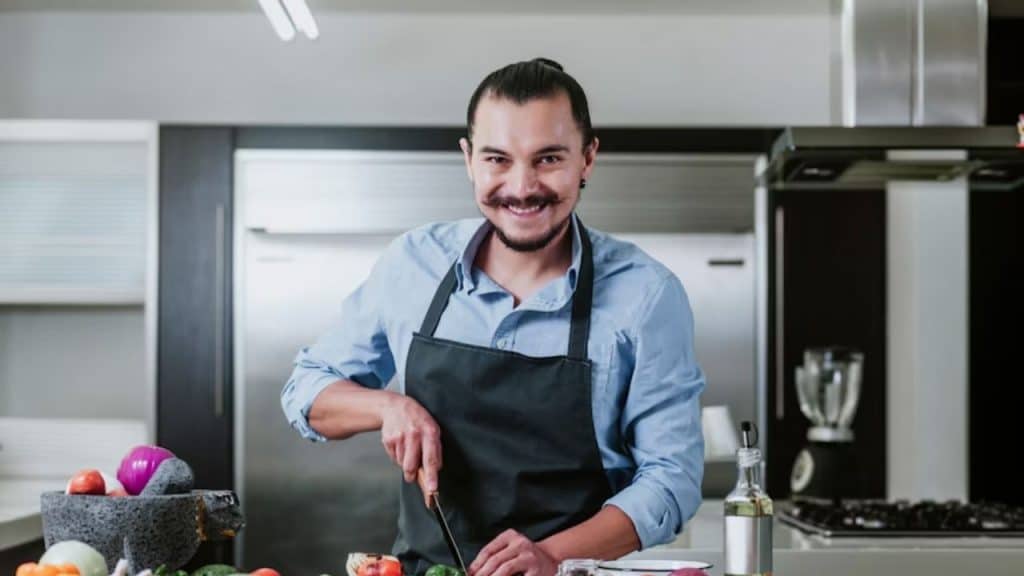 Man cooking dinner while smiling faintly