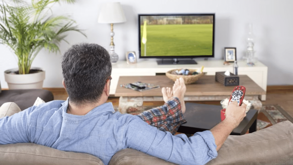 Man skipping a workout while sitting in front of the TV