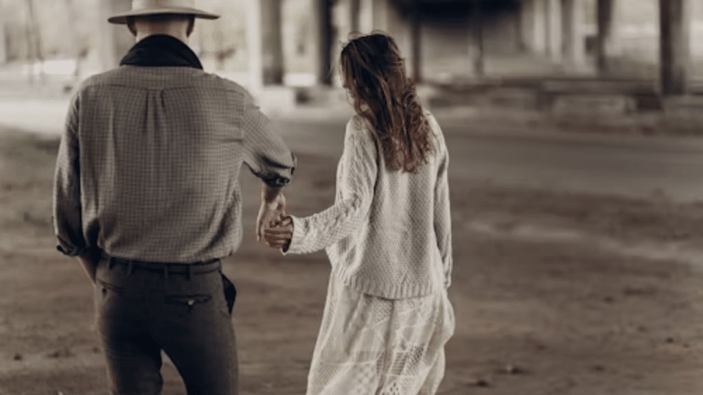 Man looking distant while woman reaches for his hand