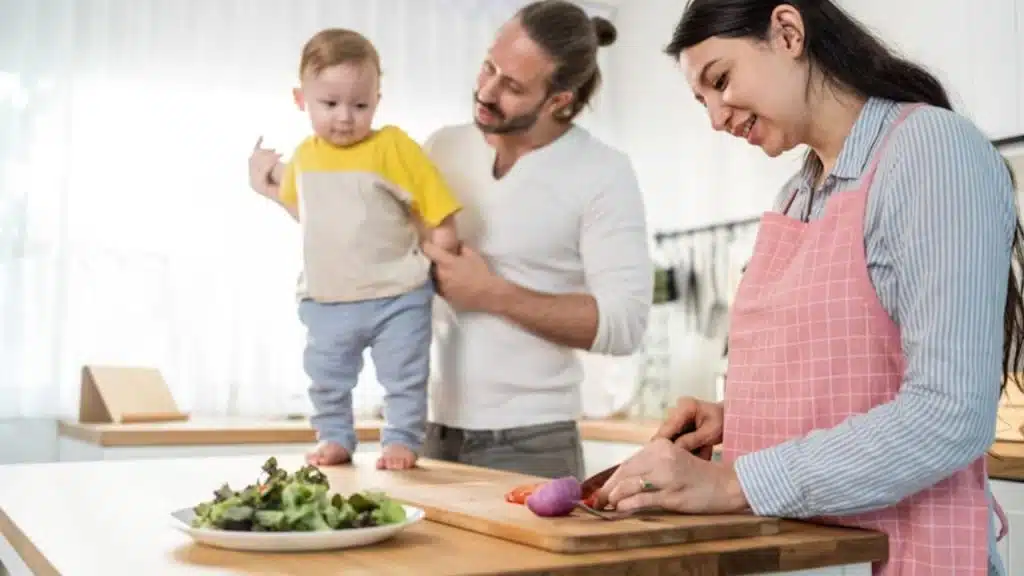 Husband takes care of a child while wife cooks for dinner