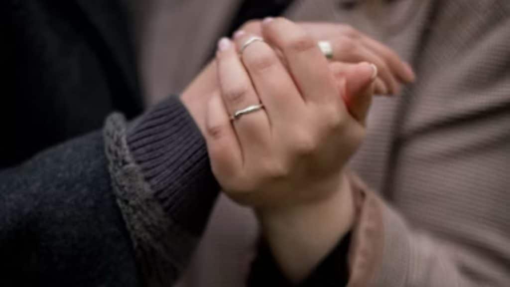 Couple holding hands with visible wedding rings
