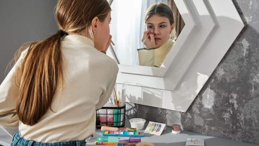 Woman applying heavy make up in the mirror which is unusual for the partner