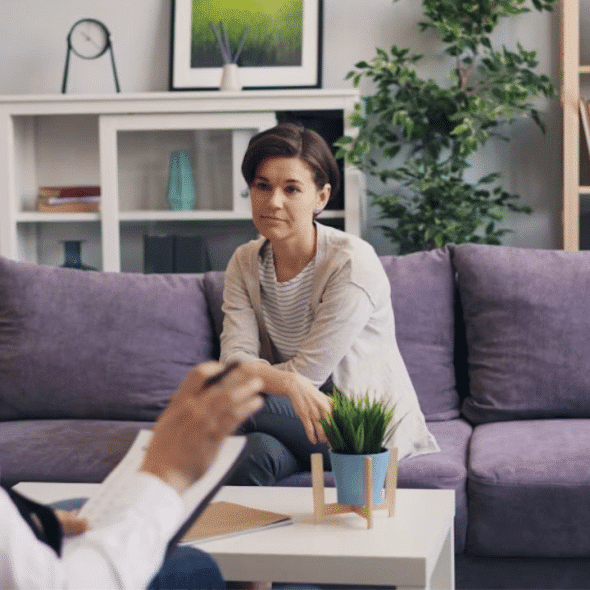Thoughtful man sitting on couch while his partner talks, looking slightly uneasy