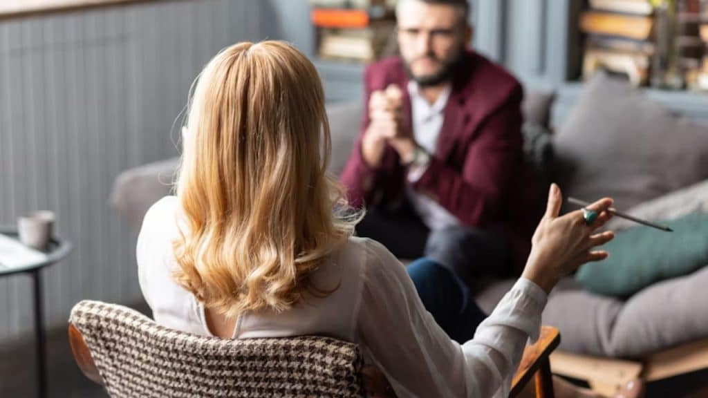 Man sitting silently as his partner criticizes him in the living room