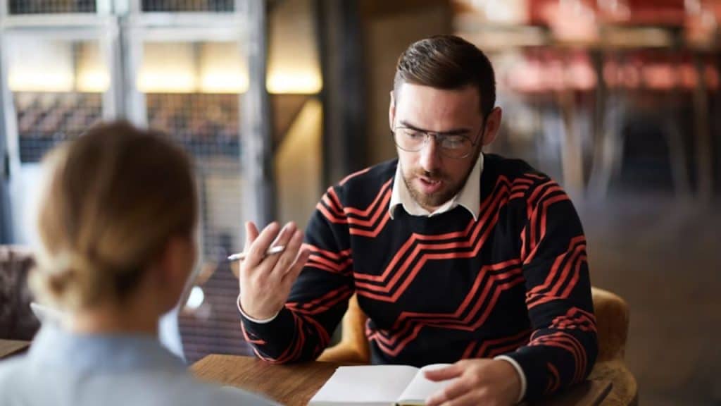 Man reviewing receipts at a table while his partner avoids eye contact