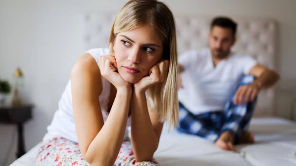 Man trying to make eye contact on bed while his partner avoids looking at him