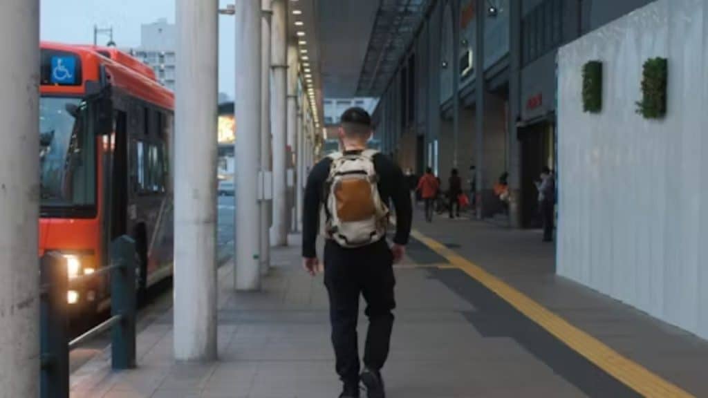 Man leaving home with a bag while his partner smiles behind him