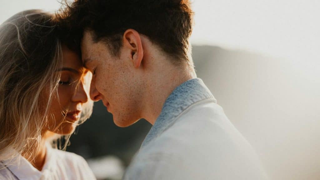 A couple sharing an intimate moment with their foreheads touching.