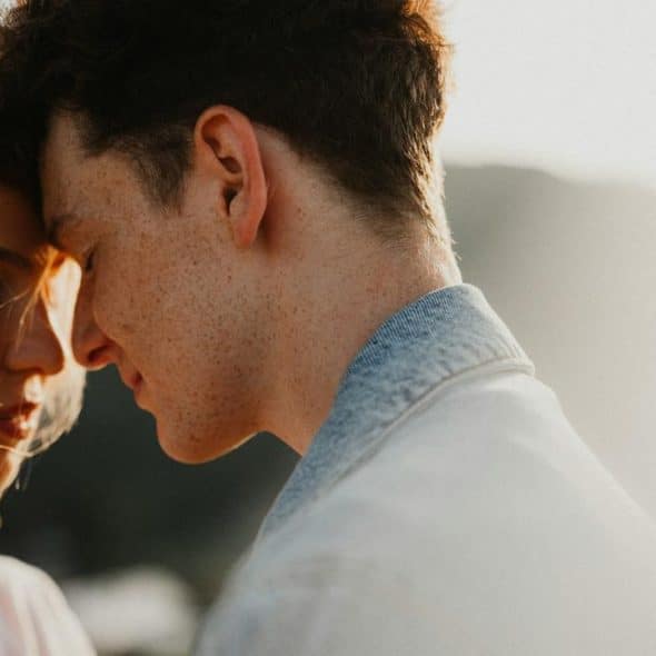 A couple sharing an intimate moment with their foreheads touching.