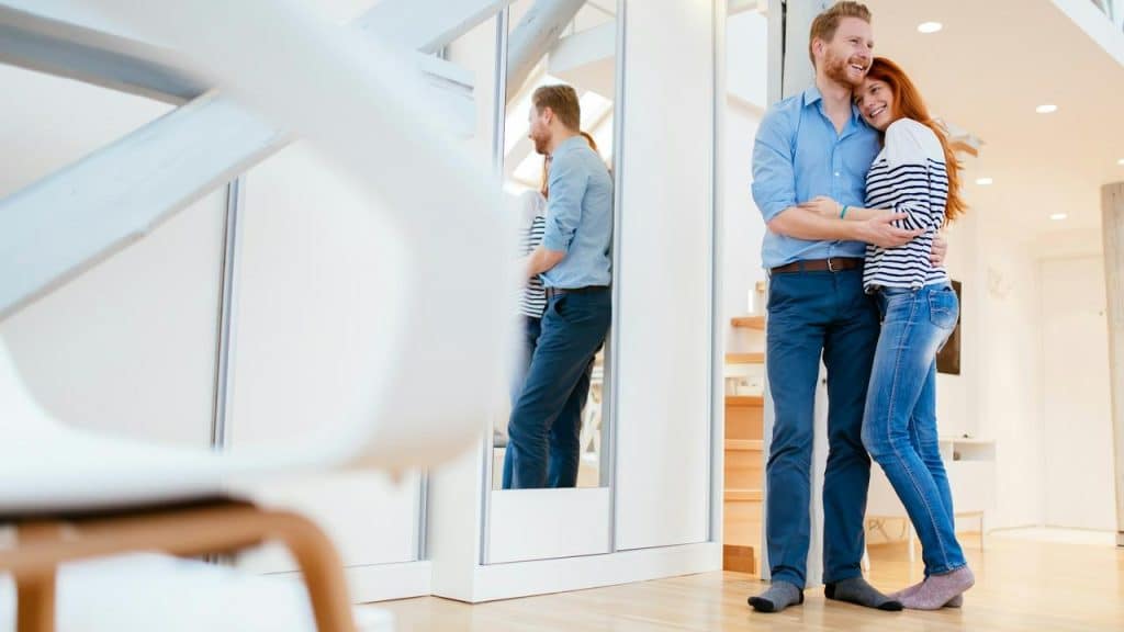 A happy couple hugging and smiling together at home.