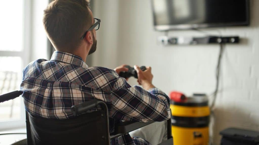 A man in a wheelchair playing video games on a TV.