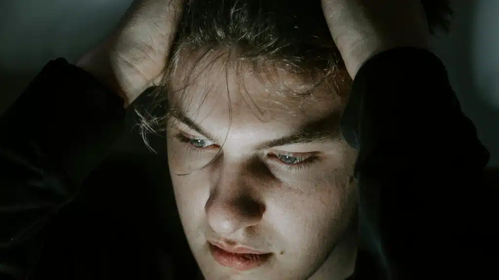 A person holding their head with both hands, looking stressed or deep in thought.