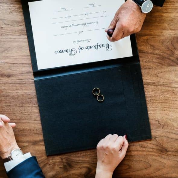 A divorce certificate with two wedding rings on a table.