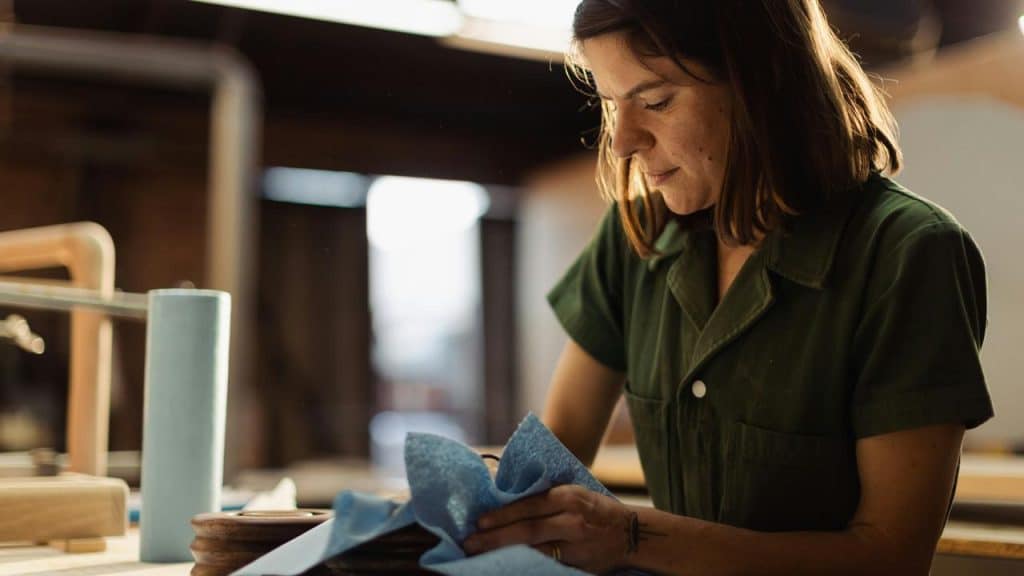 A woman working with wood, using a cloth to polish or clean it.