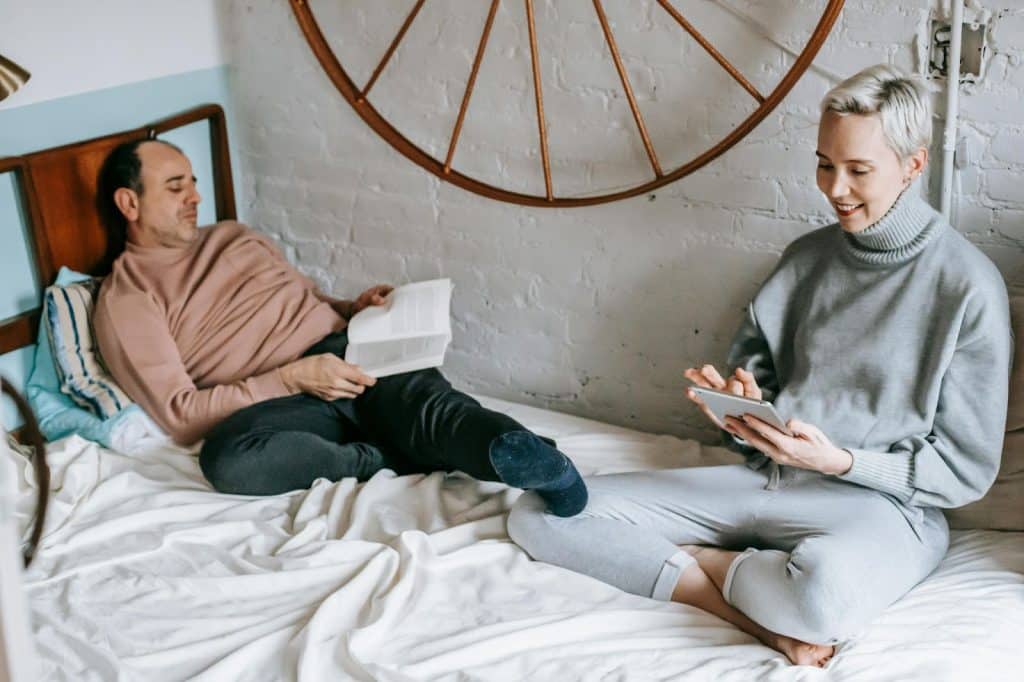A husband reading a book and a wife using a phone