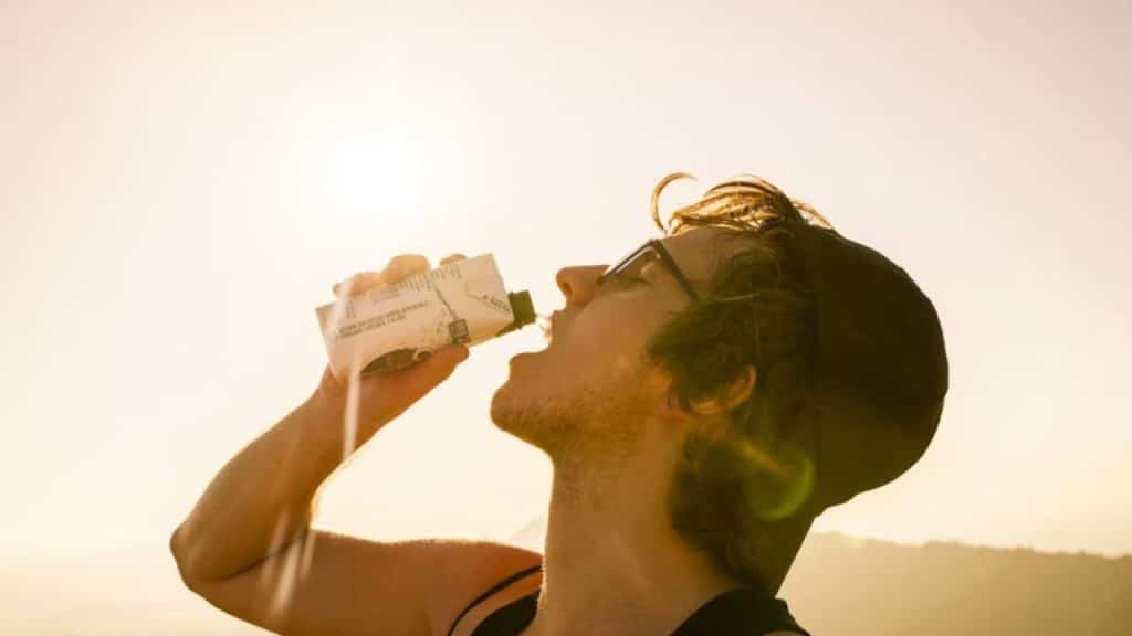 A man drinking water after a morning workout in a park
