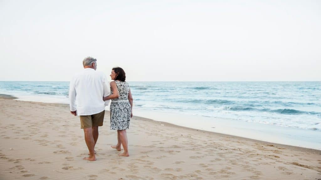 A mature couple walking down by the beach