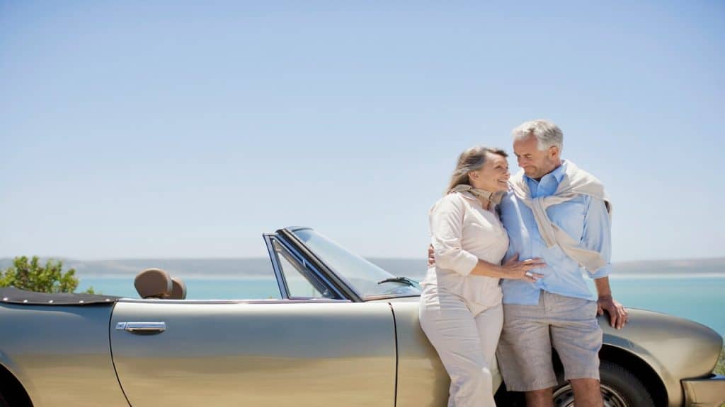A mature couple standing beside a car