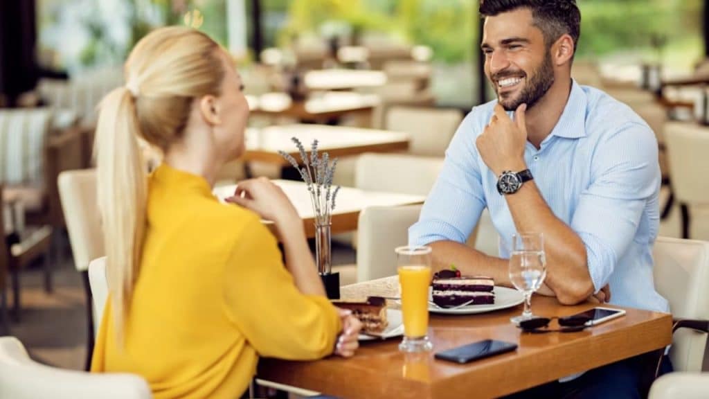 Man sitting at a café listening attentively to a woman across the table