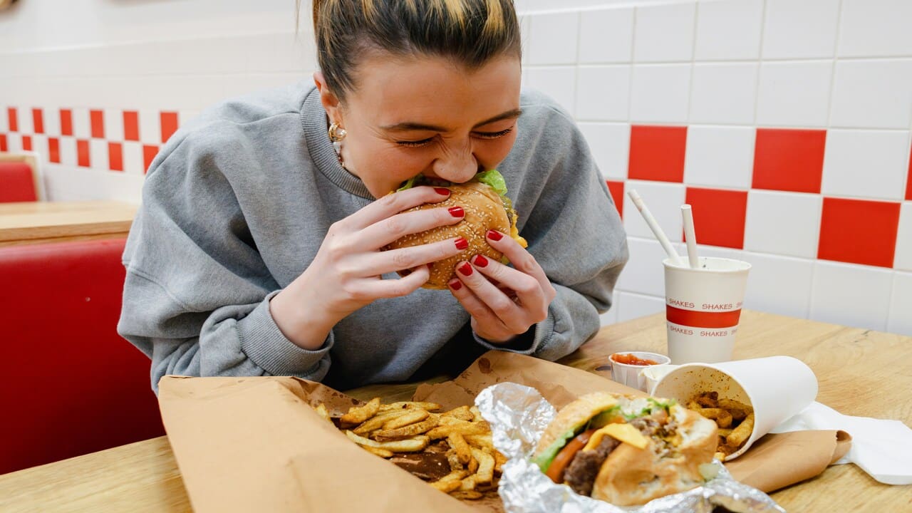 A woman eating two burgers.