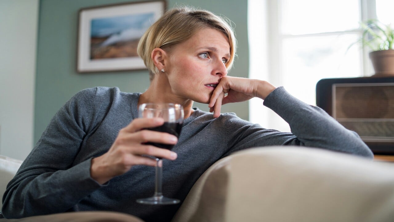 A woman looking stressed while drinking.