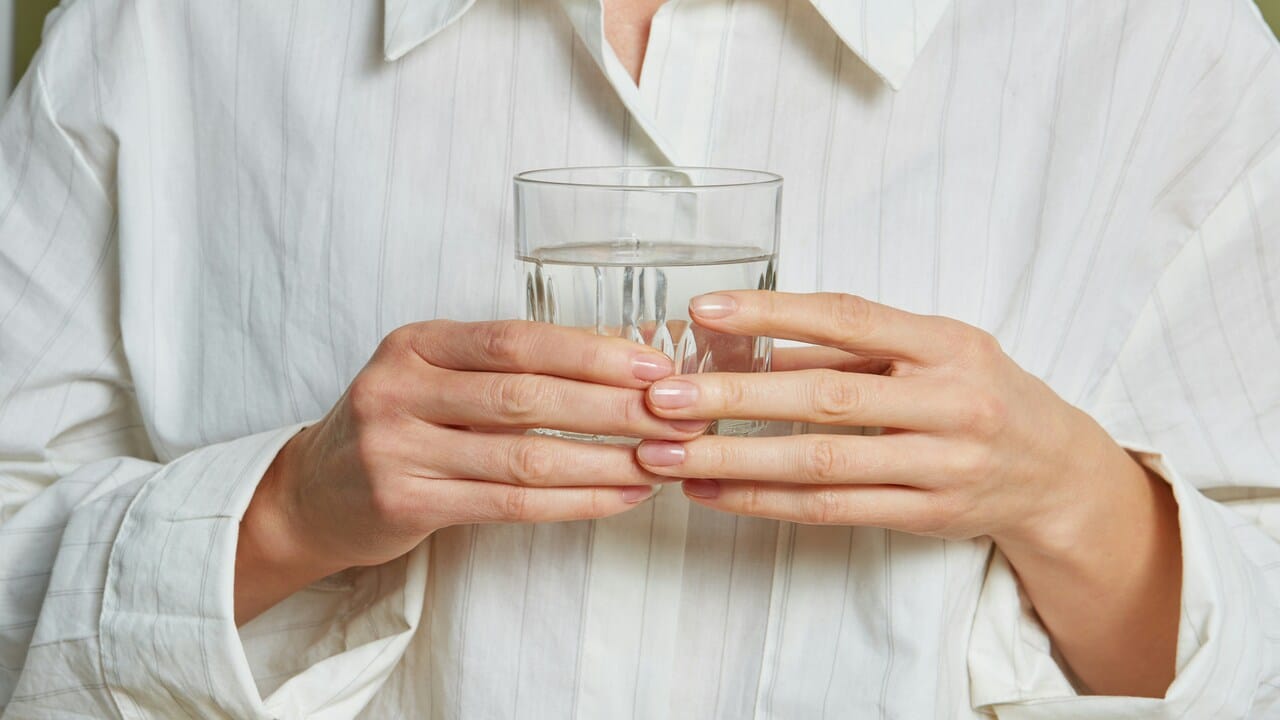 A person holding a glass of water.