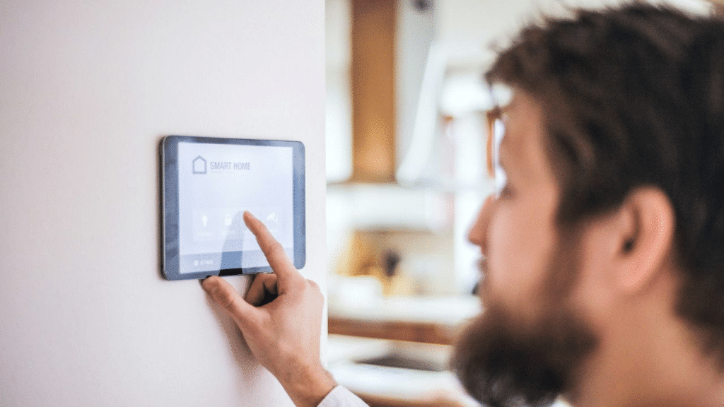 A man touches a wall-mounted smart home control panel.