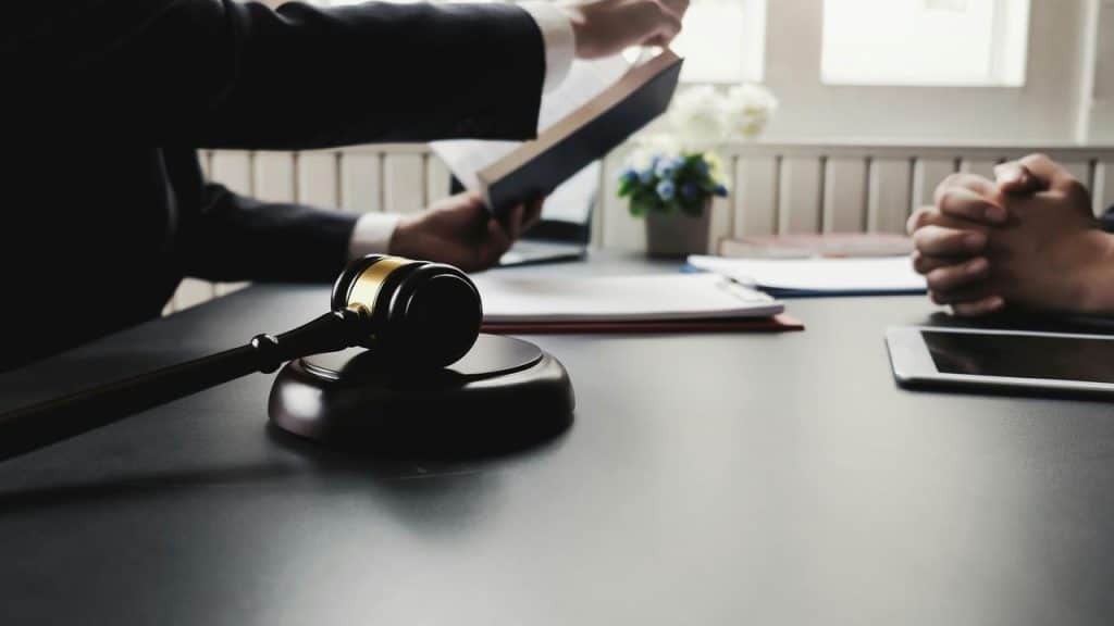 A lawyer showing a document during a meeting with a gavel on the desk.