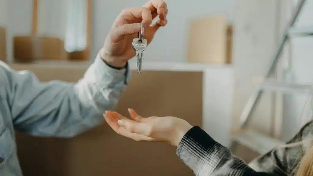 A person handing over house keys to another person indoors.