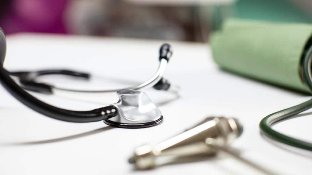 A stethoscope and medical instruments placed on a white surface.