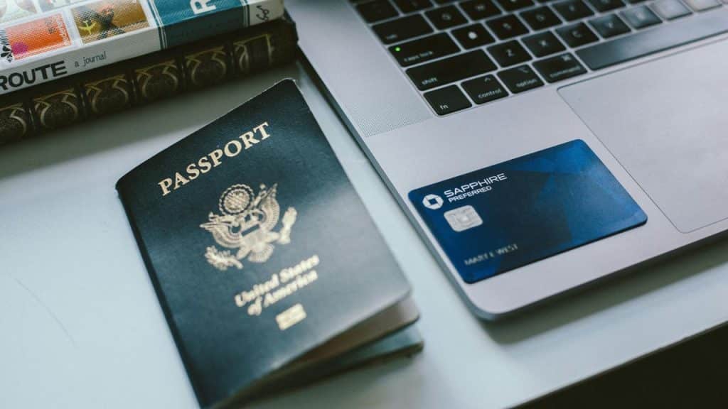 A United States passport and a credit card placed next to a laptop.