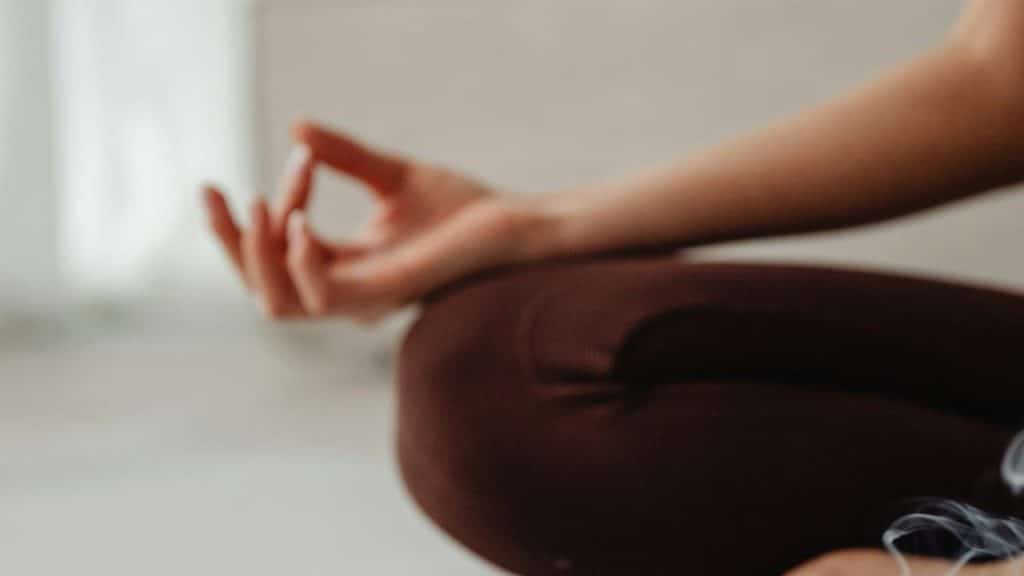A person sitting cross-legged with a hand in a meditation pose.