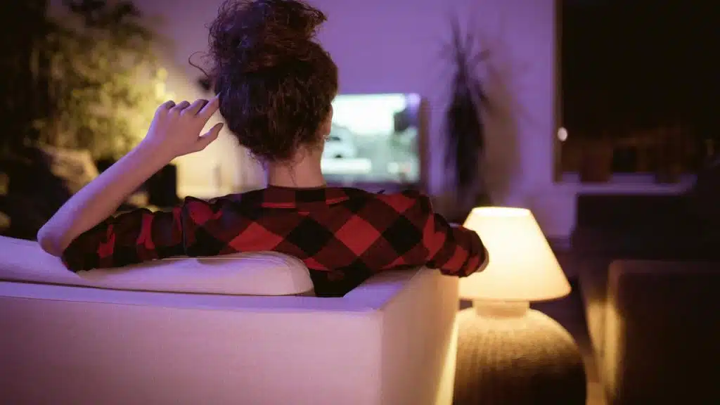 Woman sitting on a sofa watching TV.