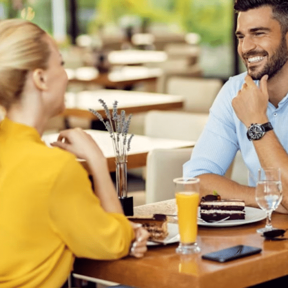 A man and woman meeting at a café for the first time, both smiling warmly