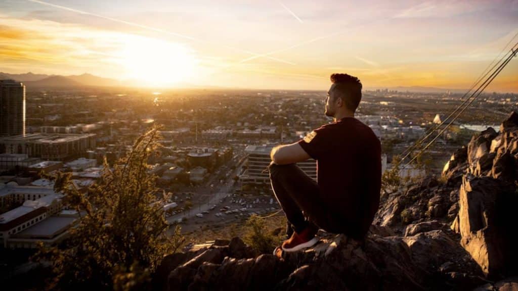 Man sitting peacefully on top of a rock practicing mindful breathing