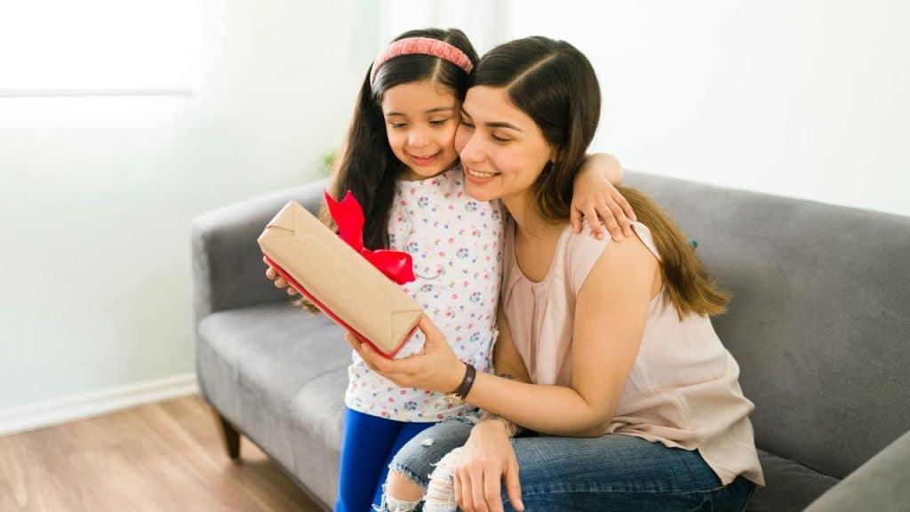 A mother and her daughter looking at a gift box together.