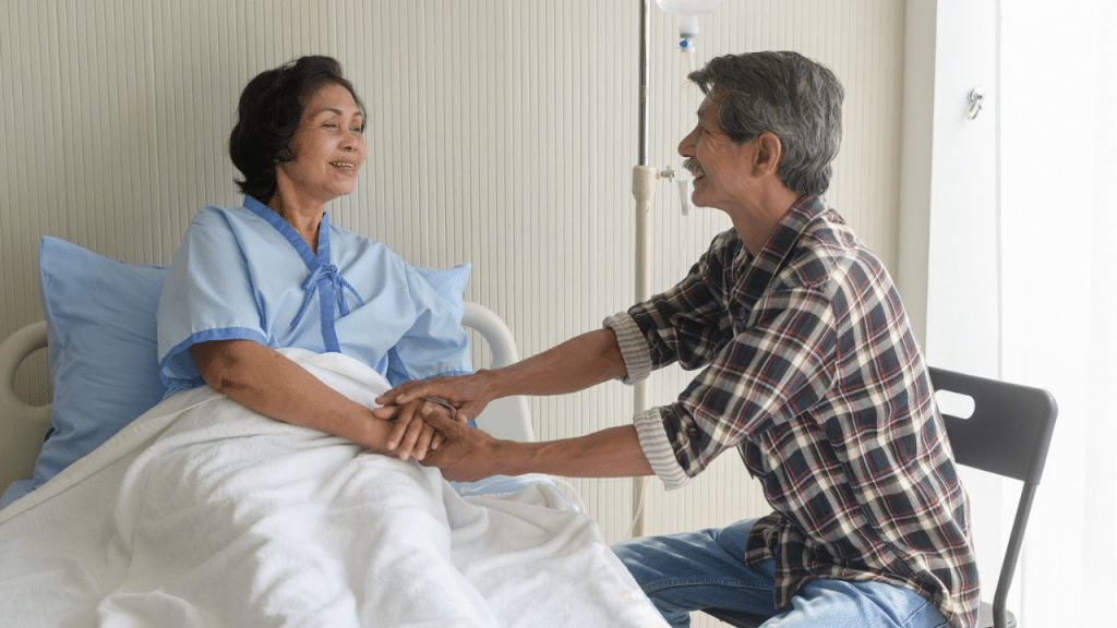 A happy, middle-aged man in a flannel shirt smiles while holding hands with a patient.