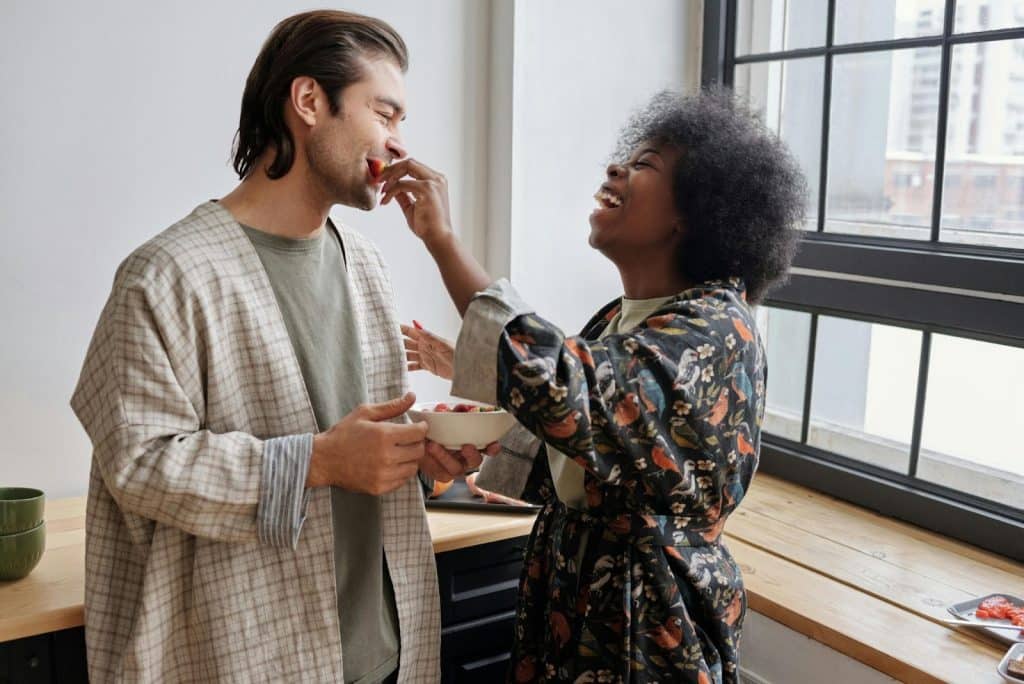 A man and woman laughing at the kitchen