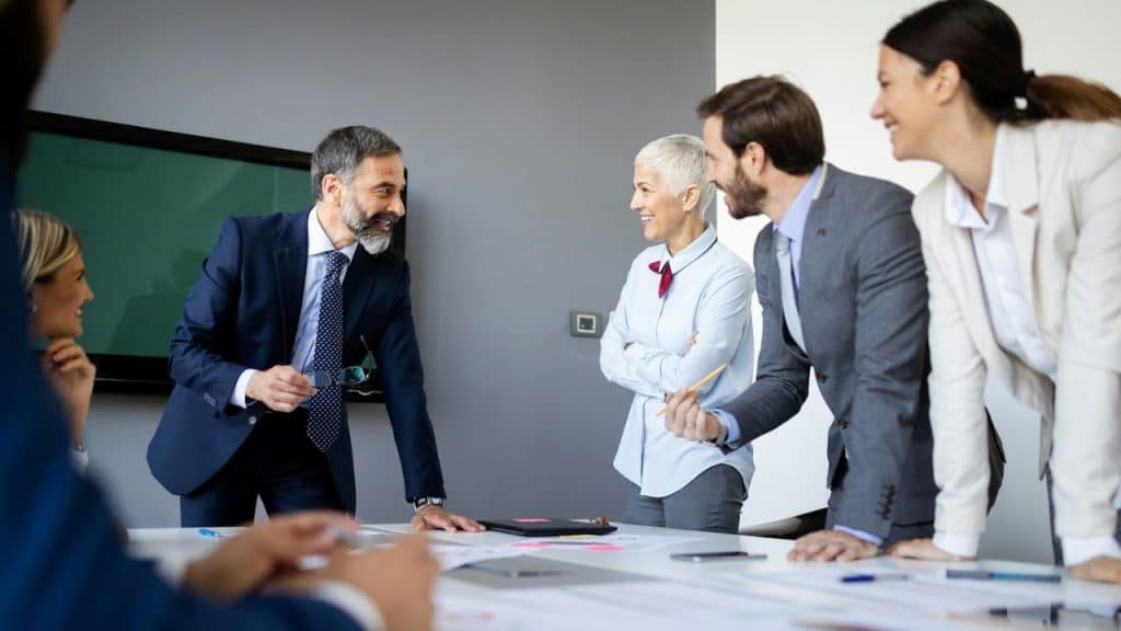 A multi-generational and diverse business team is smiling and having a productive meeting.