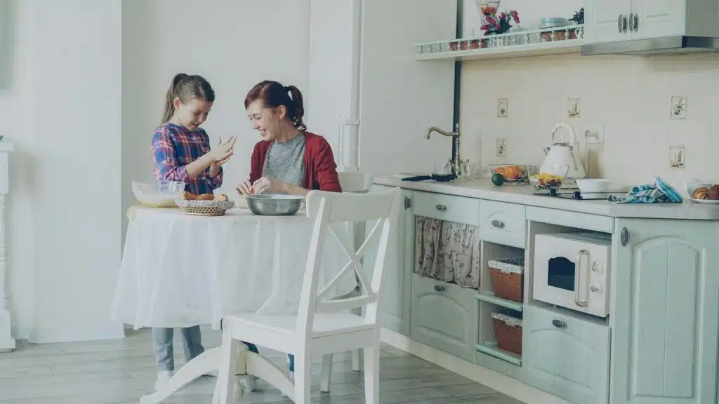 A mother and daughter cook together in a kitchen.