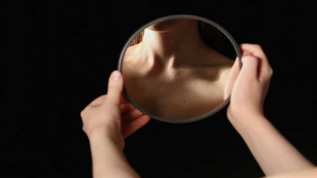 A woman looking at her neck in the mirror