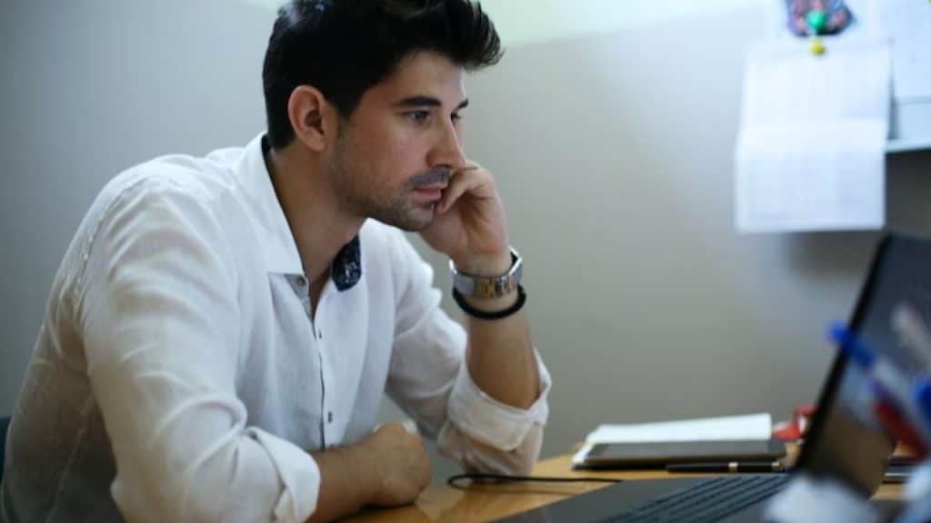 Man reviewing financial documents at home on a laptop and looking concerned