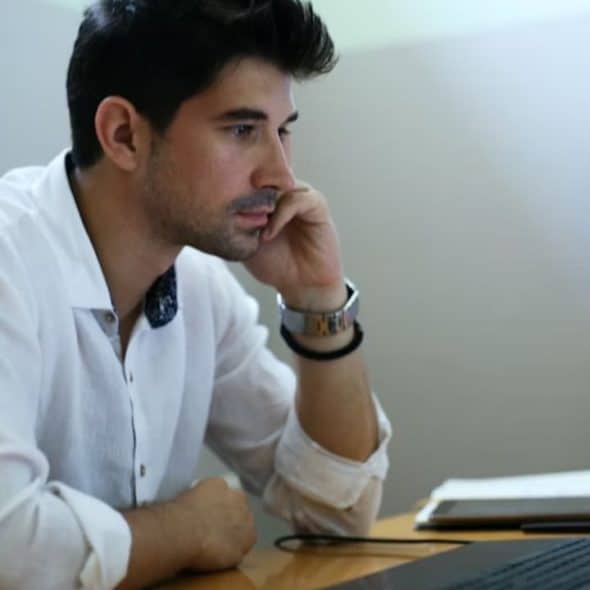 Man reviewing financial documents at home on a laptop and looking concerned
